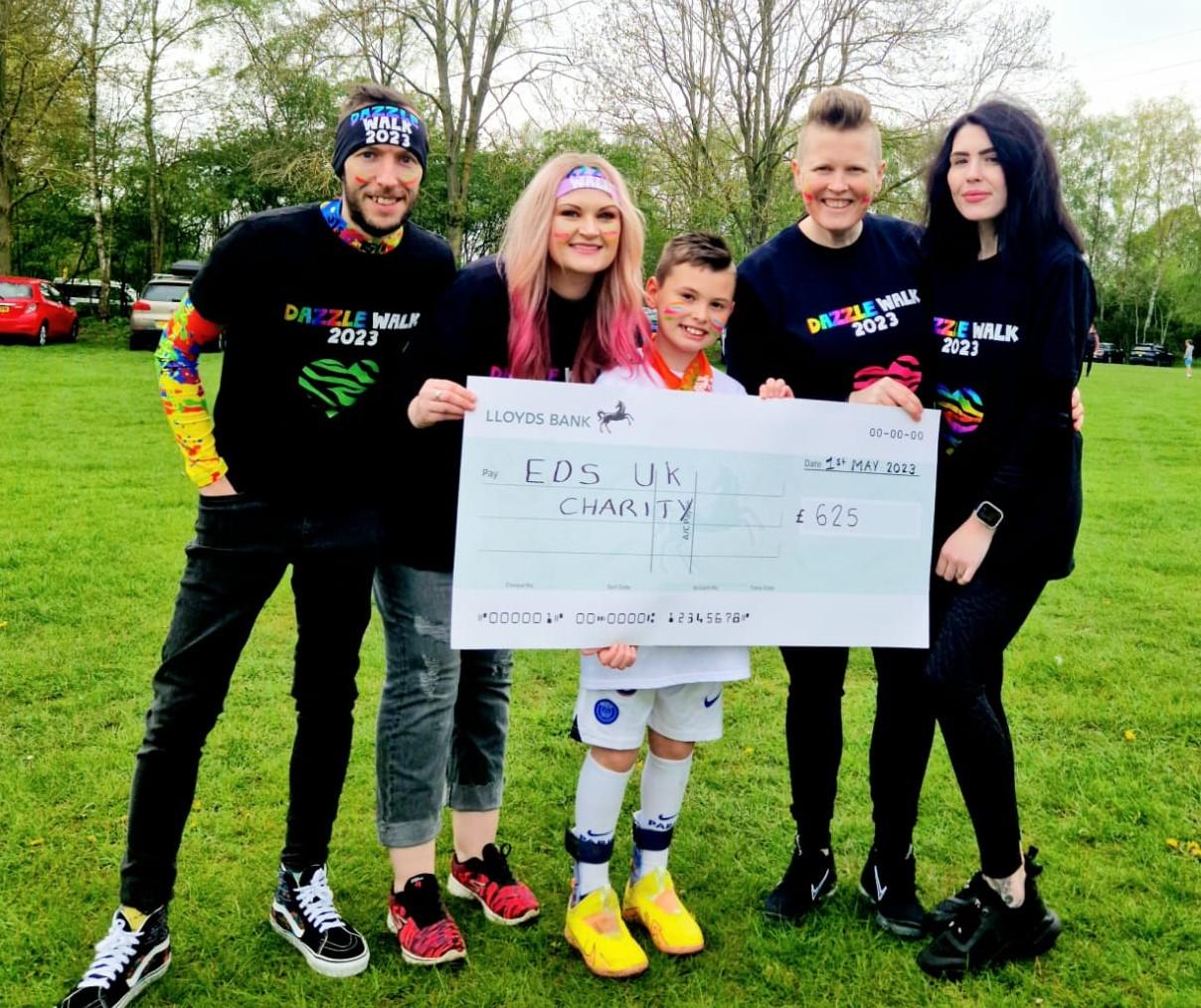 10-year-old Vinnie standing with family, holding a large cheque